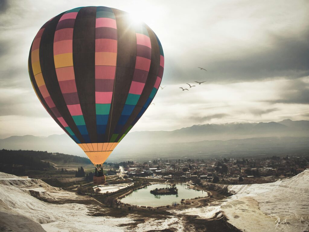 Vibrant hot air balloon soaring over Pamukkale's landscape with stunning views of Turkey's unique terraces.